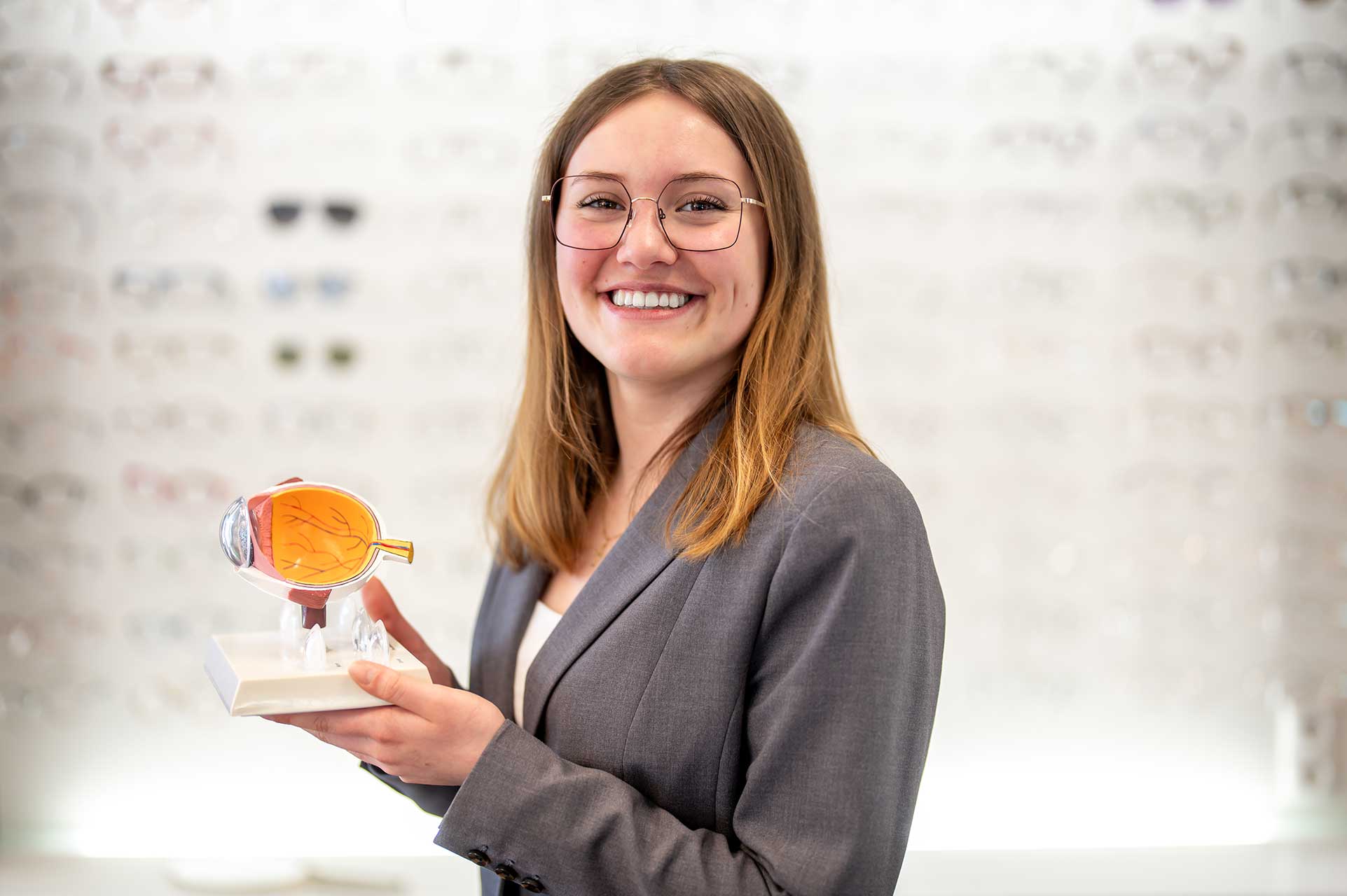 Wolff-Optic-0326_Sonja-Lehmann-Brillenwand Zwei Frauen und ein Mann arbeiten gemeinsam am Bildschirm im Optikgeschäft von Wolff Optic in Teltow.